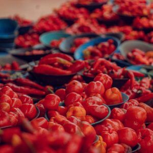 Colorful display of fresh red peppers and tomatoes at an outdoor market in Ife, Nigeria.