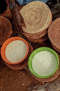 Hand arranging goods in a Nigerian market. Traditional crafts and dairy products displayed.